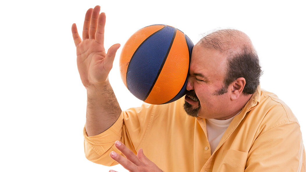 Man getting hit in the face with a basketball